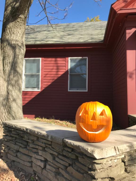 A jack-o'-lantern on a rock wall similar to what you'll see at the Halloween Parade