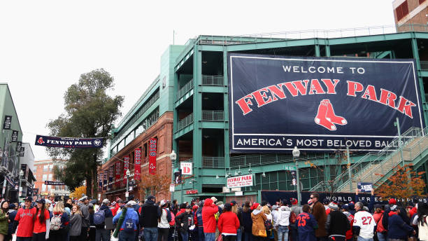 Red Sox Game Outside Fenway Park on the street with lots of fans. A sign saying Welcome to Fenway Park. America's Most Beloved Ballpark tourist attraction