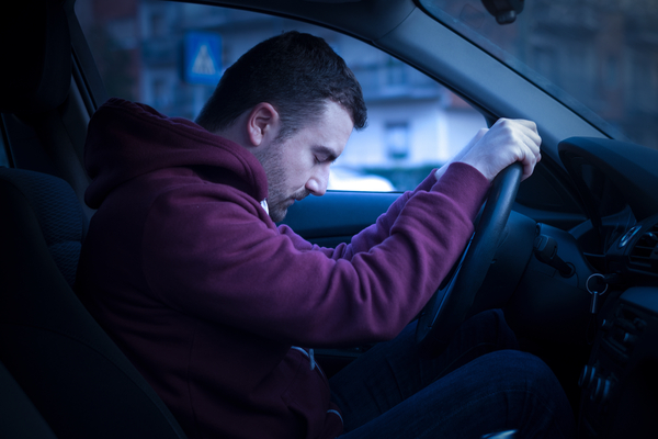 man sleeping at the wheel in his car