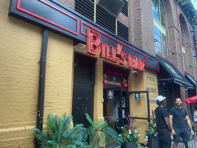 The exterior of Bill's Bar on Lansdowne St. in Boston, flanked by two doormen.